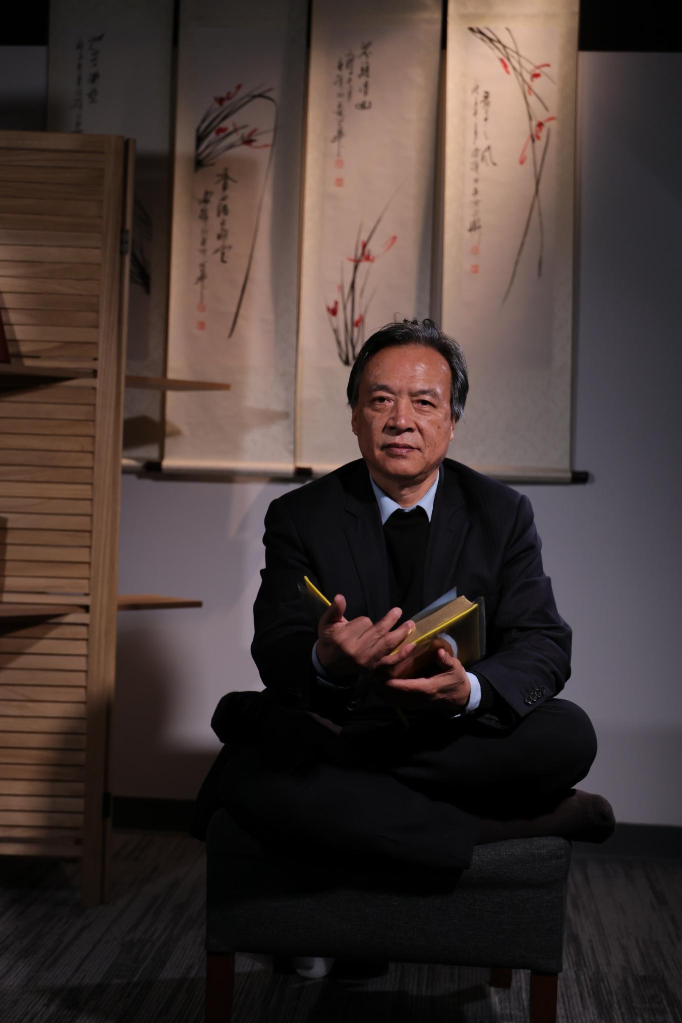 归真书画院主理人盘坐于兰花条屏前的肖像